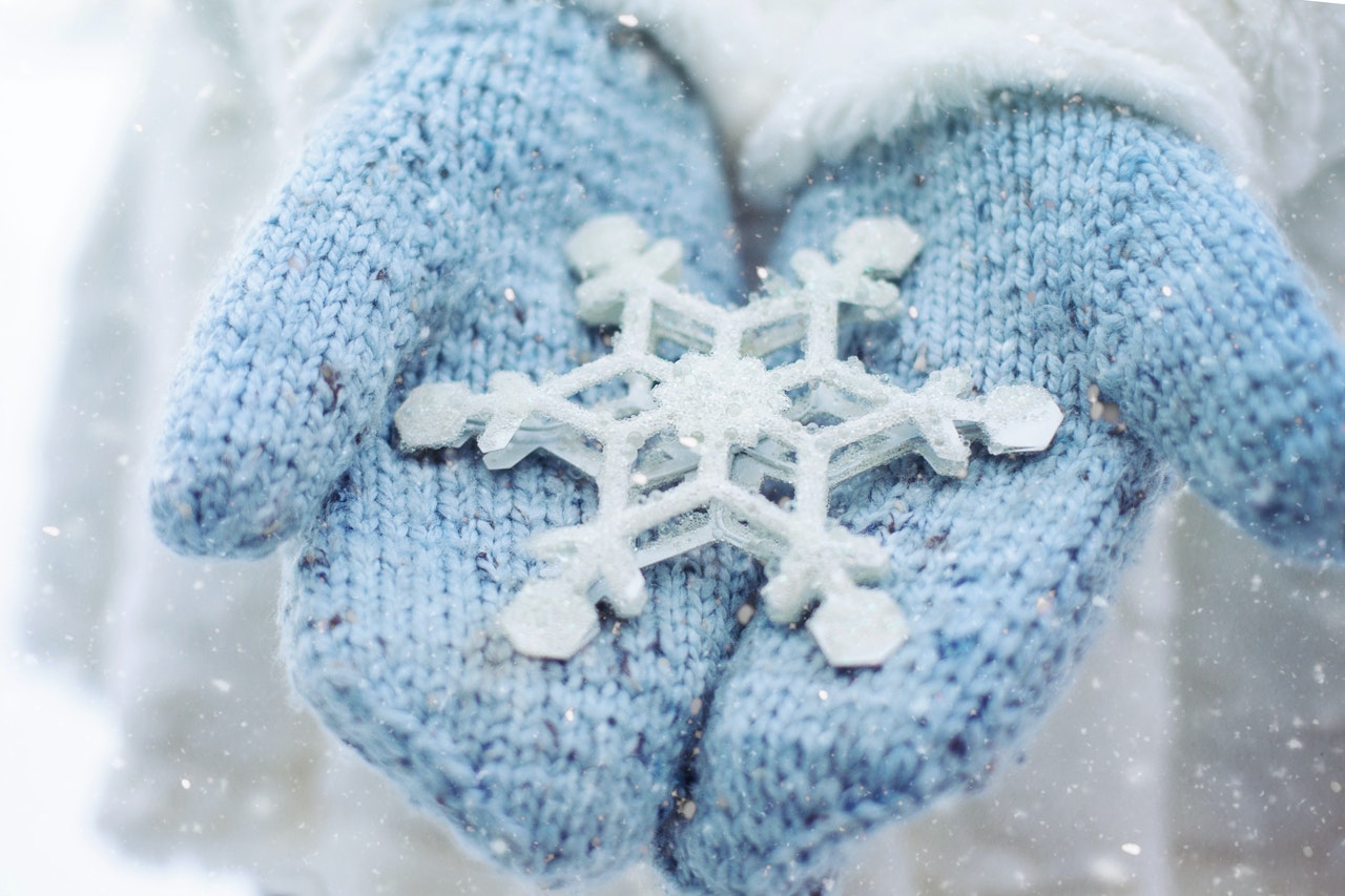 A woman wearing blue mittens holding a large snowflake