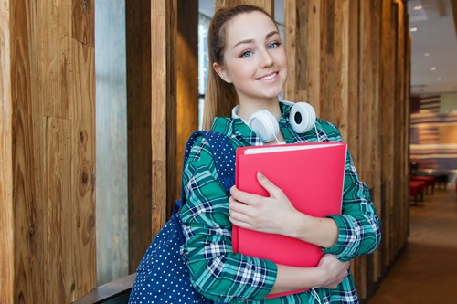 A photo of a smiling female student holding a red folder