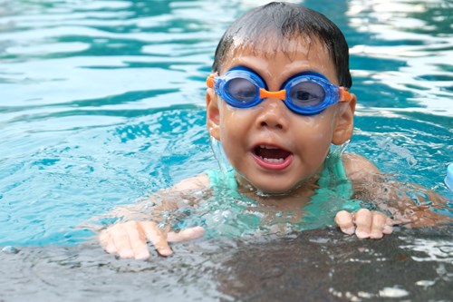 A young boy swimming wearing a pair of goggles