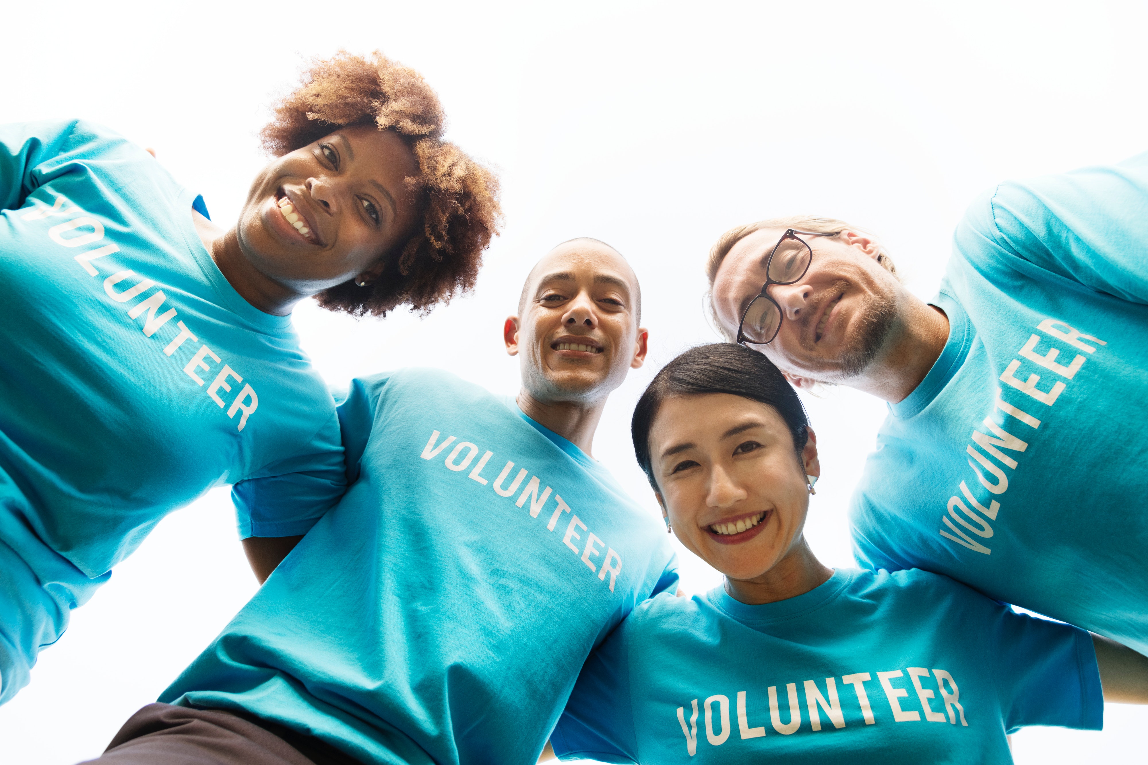 Four smiling people wearing blue volunteer t-shirts