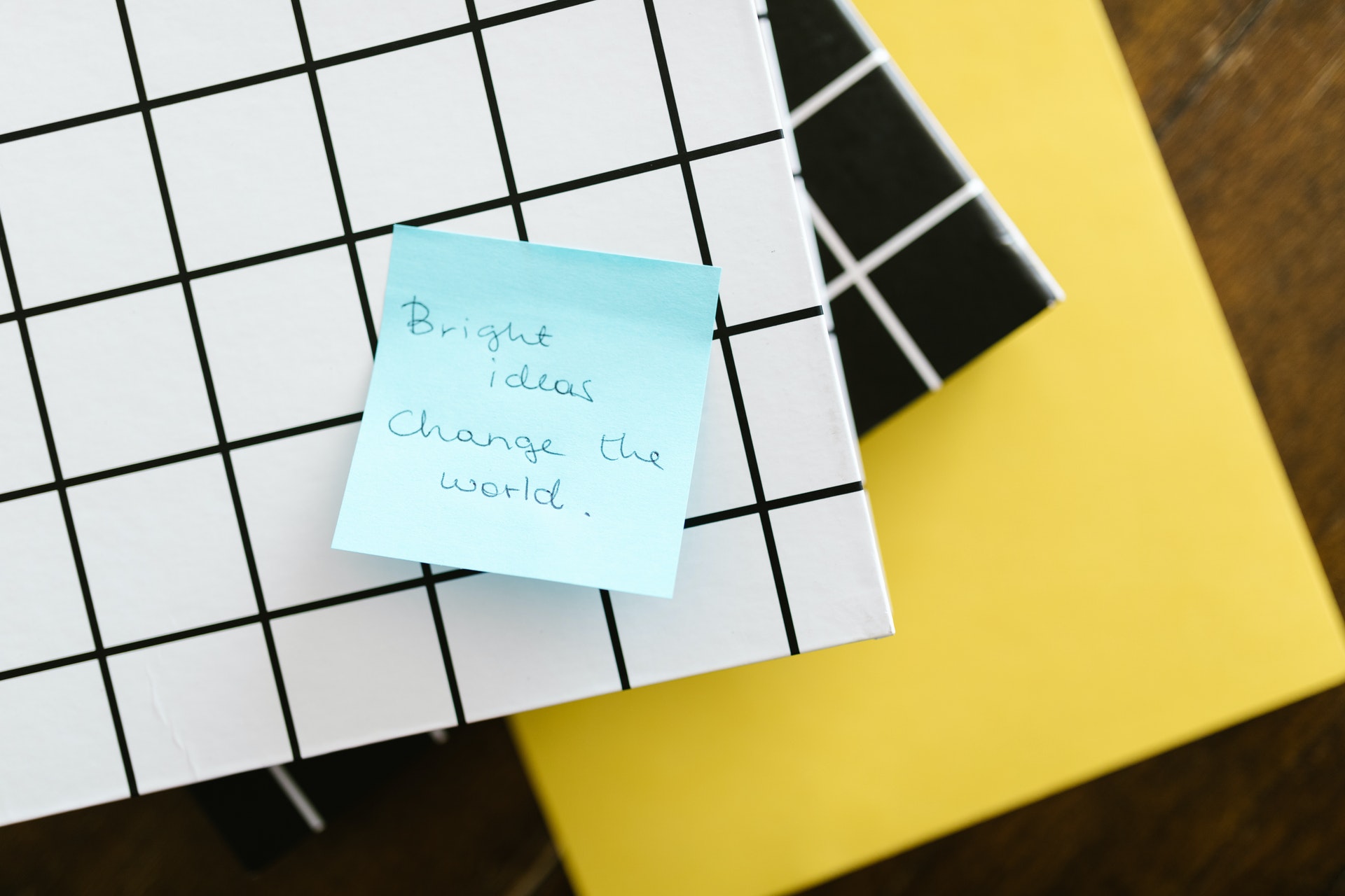 A blue sticky note on a folder with the written message bright ideas change the world