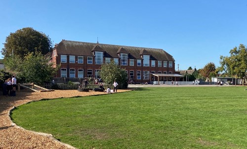 picture of the school which is red brick from the outside with grass at the front