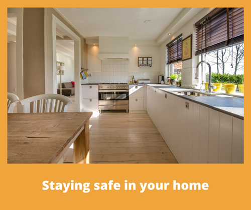 A kitchen with white cupboards and a wooden dining table with the title staying safe in your home