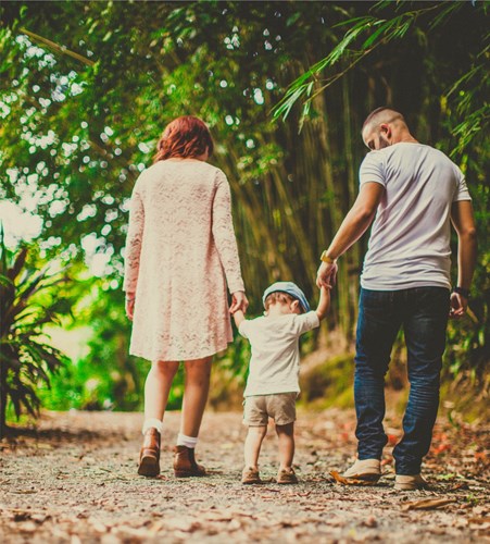 A photo of a toddler walking with his parents