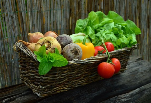 A photo of vegetables and salad in a wicker basket