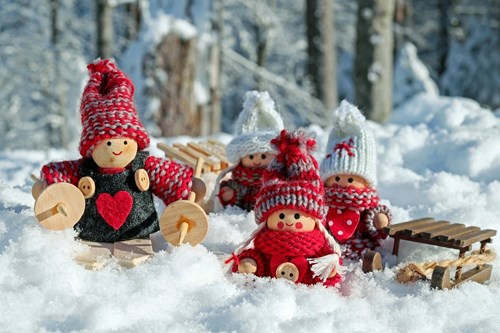 A photo of wooden Christmas decorations in the form of little people in the snow