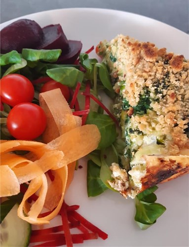 A photo of spinach, leek and cheese crumble served with salad